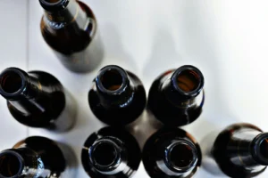 Empty beer bottles seen from above against a white background show the bleakness associated with alcohol use disorder, often treated with Antabuse generic name alternatives.
