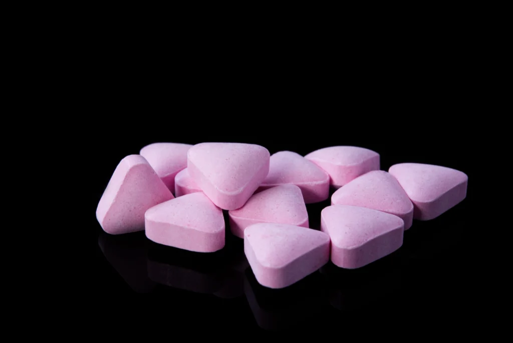 How Long Do Muscle Relaxers Last? Pink triangular pills on a dark surface.